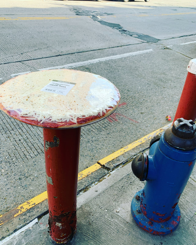 A frozen pizza sitting on a post next to a fire hydrant