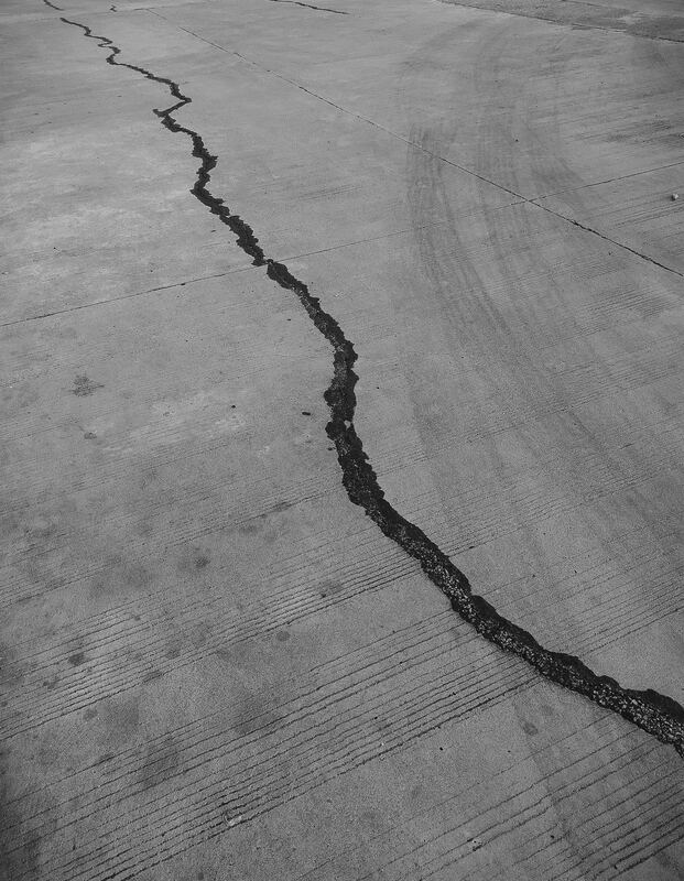 A gray and black photo of cracked cement